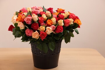 Bouquet of beautiful roses on wooden table against beige background