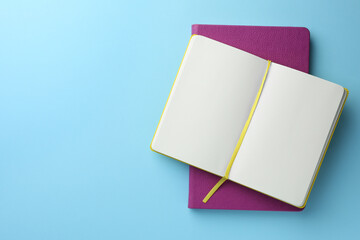 Different notebooks on light blue background, top view. Space for text