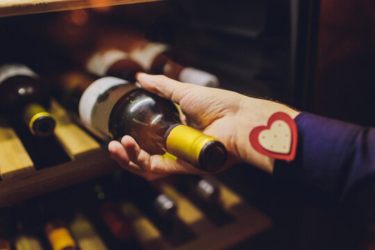 Sommelier with wine bottle near rack at store.