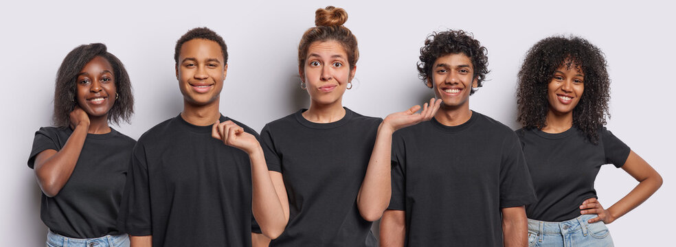 Positive mixed race millennial people smile toothily one expresses hesitation and spreads palms sideways dressed in casual black t shirts look directly at camera isolated over white background.