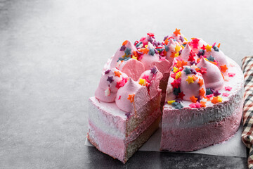 Pink Sponge cake decorated with small meringue on top on gray background