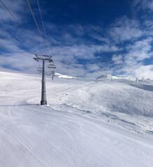 Ski slope, chair-lift on ski resort and blue sky with sunlight clouds - 701459188