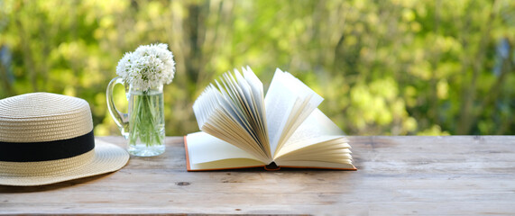 paper book, bouquet of wild garlic flowers on old wooden table in garden, blurred natural landscape background with green foliage, Ecology concept, nostalgia knowledge, education, energy of nature - obrazy, fototapety, plakaty