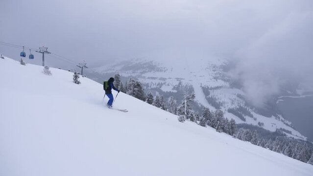 backcountry skier makes short turns in powder, deep snow, follow cam