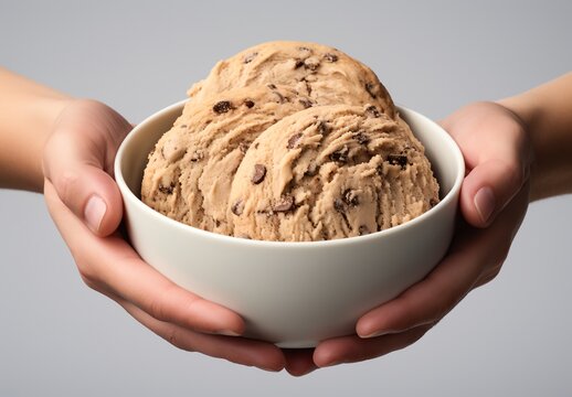 a person holding a bowl of cookies with chocolate chips