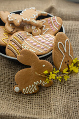 Easter holiday cookies servet on dish on the table with jute tablecloth, group of color painted gingerbread sweets springtime