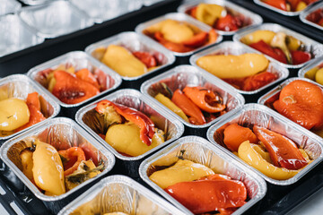 Pre-portioned Gourmet Roasted Bell Peppers in Trays. Close-up view of vibrant roasted bell peppers portioned in aluminum trays, prepared for a catered event or meal service.