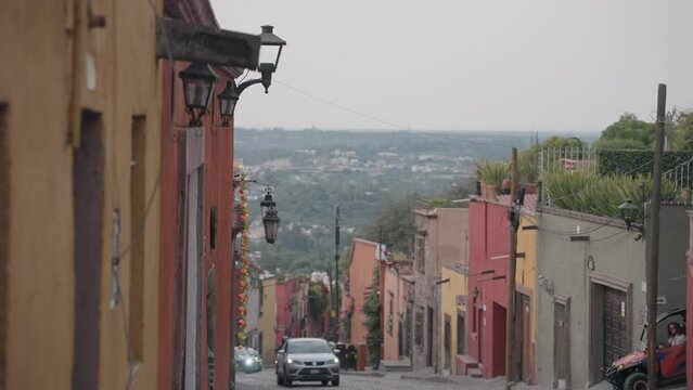 San Miguel de Allende, Mexico - November 9, 2023: Beautiful Hilly Small Narrow Street Alley with Colorful Buildings and La Parroquia de San Miguel Arc&aacute;ngel