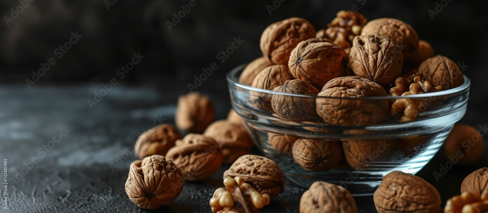 Poster walnuts in a clear glass bowl and scattered on a black table selective focus. creative banner. copys