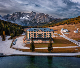 Misurina, Italy - Aerial view of Cristallo mountains of the Italian Dolomites at Lake Misurina in South Tyrol with morning autumn lights, cloudy sky and rehabilitation centre