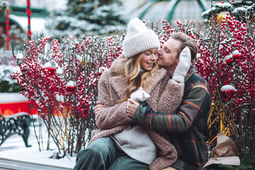 Beautiful young loving couple embracing, kissing, enjoying winter vacation, cold snowy day on a...