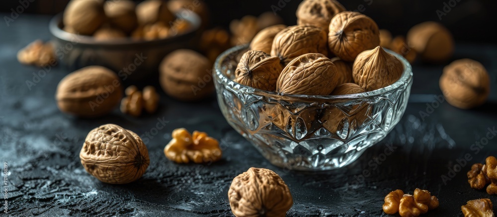 Poster walnuts in a clear glass bowl and scattered on a black table selective focus. creative banner. copys