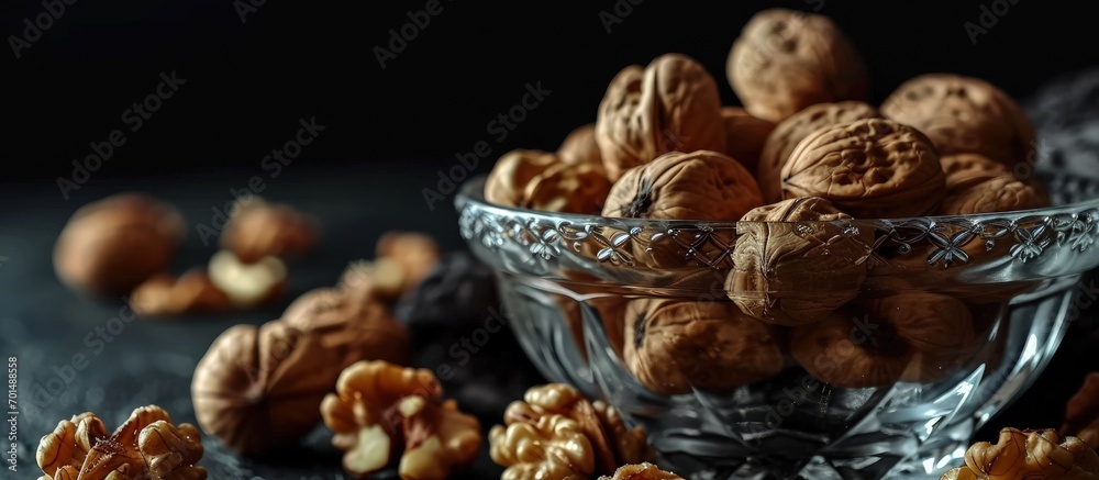 Poster walnuts in a clear glass bowl and scattered on a black table selective focus. creative banner. copys