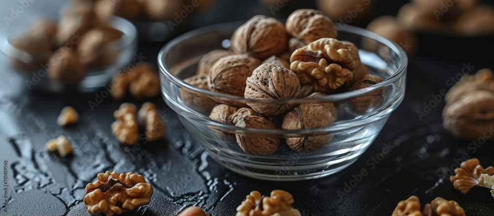 Poster walnuts in a clear glass bowl and scattered on a black table selective focus. creative banner. copys