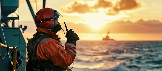 Marine Deck Officer or Chief mate on deck of offshore vessel or ship wearing PPE personal protective equipment helmet coverall He holds VHF walkie talkie radio in hands. Creative Banner - obrazy, fototapety, plakaty