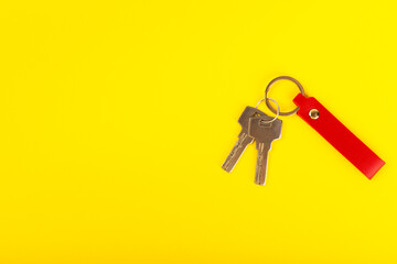 Leather keychain with a key ring on a yellow background. Concepts for real estate and moving home or renting property. Buying a property. Mock-up keychain.Copy space.