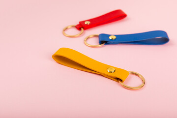 Leather keychain with a key ring on a pink background. Concepts for real estate and moving home or renting property. Buying a property. Mock-up keychain.Copy space.