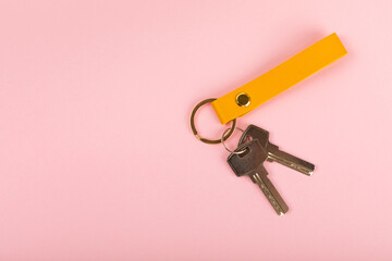 Leather keychain with a key ring on a pink background. Concepts for real estate and moving home or...