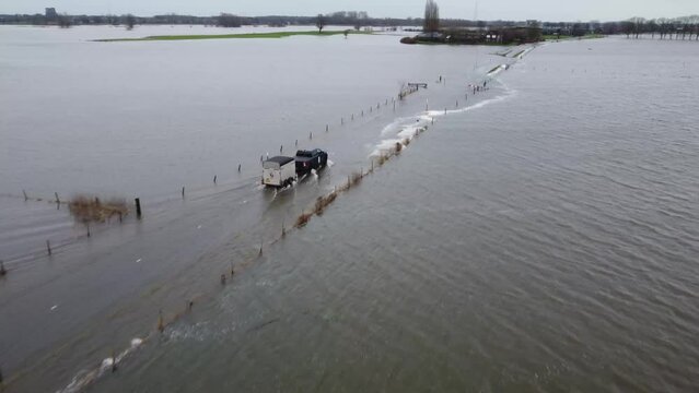 Hattem, the Netherlands - December 27th, 2023: aerial view of truck driving over flooded road. After weeks of heavy rainfall water levels rise to critical hights at the IJssel river.