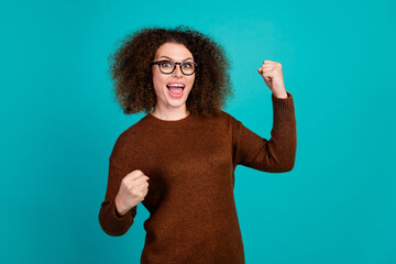 Portrait of young successful businesswoman pullover raise fists up when achieve new knowledge in ms...