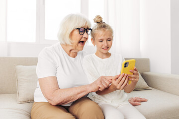 Granddaughter education family bonding togetherness phone smiling selfie hugging grandmother child sofa
