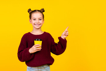 Portrait of small positive person beaming smile hold coffee cup indicate finger empty space isolated on yellow color background