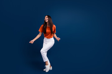 Fototapeta na wymiar Full length photo of adorable sweet woman dressed orange t-shirt enjoying discotheque empty space isolated dark blue color background