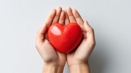 Obraz premium Palms cradle a smooth red heart, a universal sign of love and health on World Health Day.