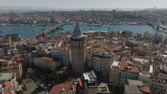 Orbit shot around old Galata Tower. Popular tourist landmark in historic urban borough. City with bridges and mosques in background. Istanbul, Turkey
