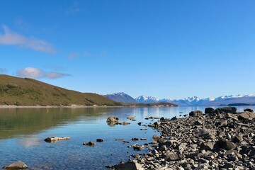 New Zealand lake with rocks and mirror lake with mountains 