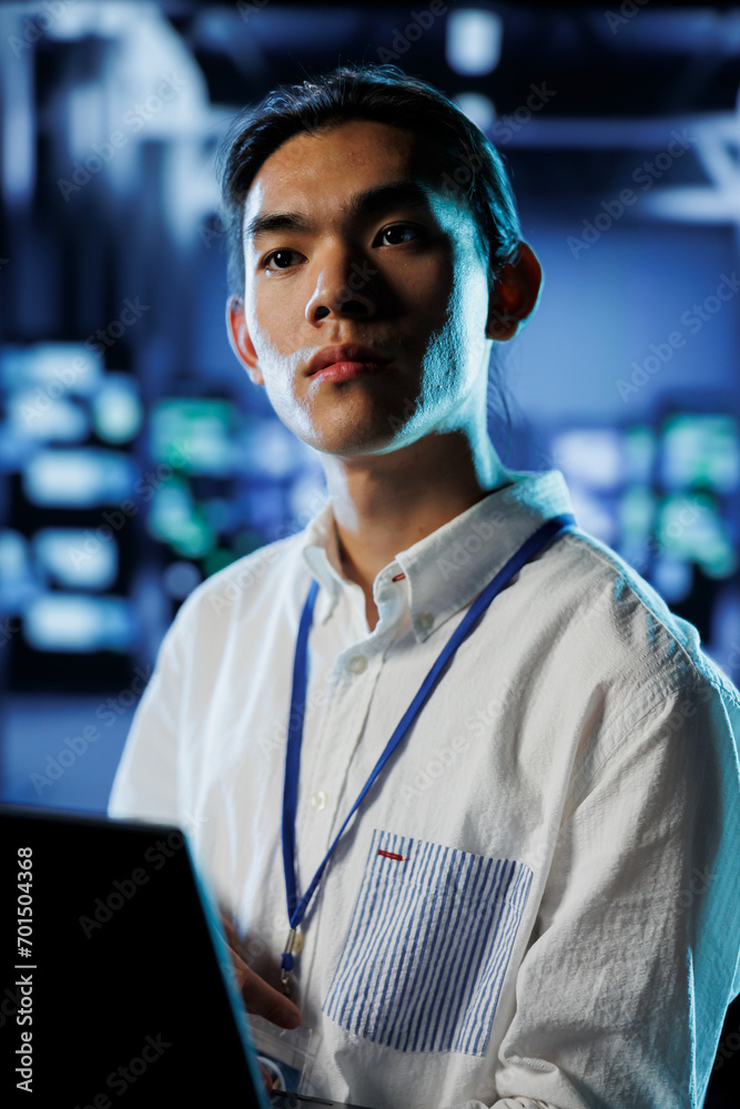 Poster computer scientist in data center uses laptop to prevent system overload during peak traffic periods