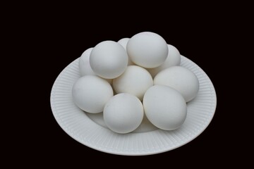 white chicken eggs on a plate on a black background