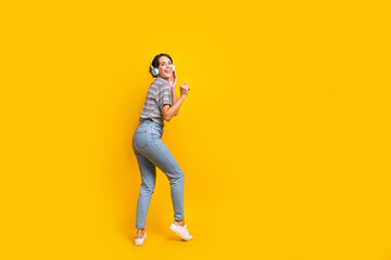 Fototapeta na wymiar Full size rear profile portrait of carefree positive girl enjoy favorite playlist empty space isolated on yellow color background