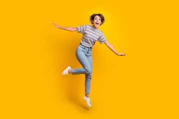 Fototapeta na wymiar Full size portrait of astonished carefree girl hands wings flying jumping isolated on yellow color background