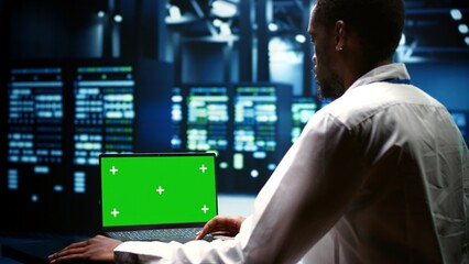 System administrator examining server rigs performance trends. Expert using green screen laptop to discover data center operational issues arising due to high CPU usage and insufficient memory