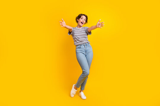 Full size portrait of astonished cheerful girl raise opened hands welcome you isolated on yellow color background