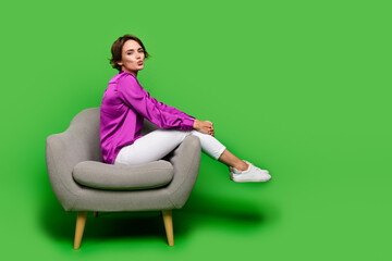 Fototapeta na wymiar Photo of young lady coquette girlfriend sitting armchair send air kiss flirting in office to colleagues isolated on green color background