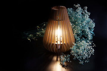 An eco-friendly wooden night light - an interior table lamp shines next to the white flowers of...