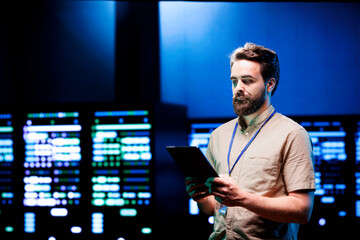 Admin walking in data center supporting AI through powerful computing operations, hosting specialized storage servers. Engineer ensuring high tech facility internal hardware functions properly
