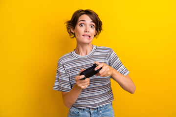 Photo of astonished focused woman dressed striped t-shirt hold playstation joystick biting lip...