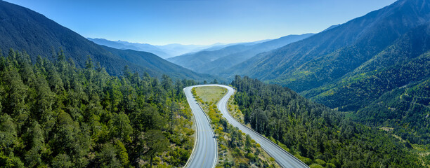 Aerial view of the road on the mountain with forest arround. - obrazy, fototapety, plakaty