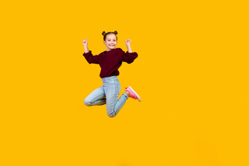 Full body portrait of overjoyed small schoolkid jumping raise fists empty space isolated on yellow...