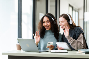 Caucasian and an African American university woman working together on a project, discussing and taking notes.