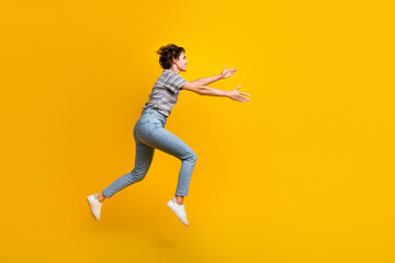 Fototapeta na wymiar Full size profile photo of sportive energetic girl jump run arms catch empty space isolated on yellow color background