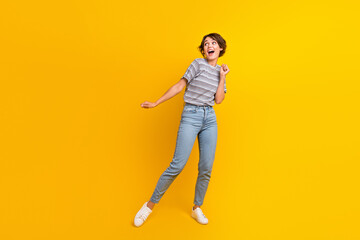 Fototapeta na wymiar Full size portrait of crazy satisfied young girl have good mood dancing empty space isolated on yellow color background