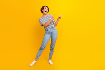 Fototapeta na wymiar Full size photo of astonished cute girl look direct fingers empty space ad isolated on yellow color background