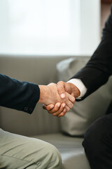close-up of two men in business suits shaking hands, likely concluding a discussion or agreement,...