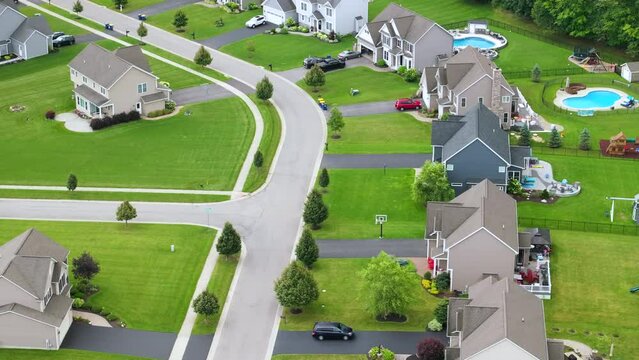 Low-density two story private homes with large lot size and green grassy lawns in summer season. Rural residential suburbs with upscale suburban houses outside of Rochester, New York