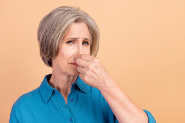 Portrait of retired person with white gray hairdo wear blue shirt fingers close nose from stinky...