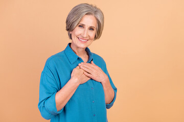 Photo of thankful positive senior woman with bob hairstyle dressed blue shirt keep hands on chest...